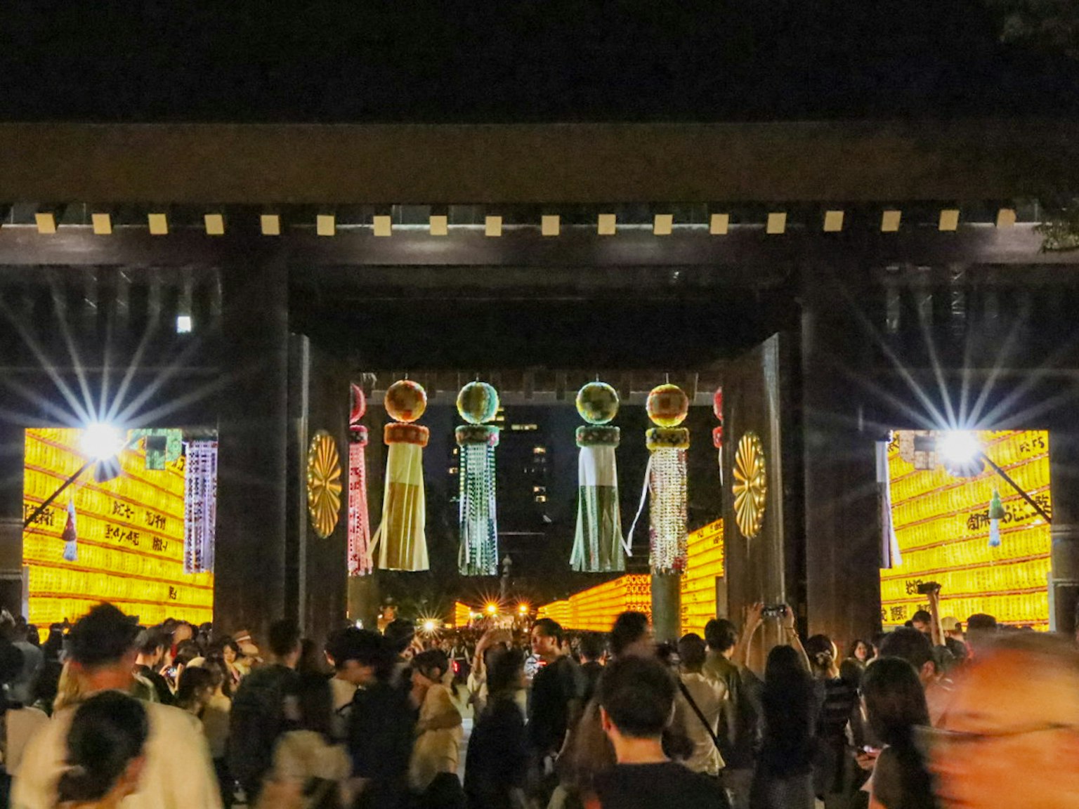 Grande porte avec des décorations colorées et des foules lors d'un festival nocturne