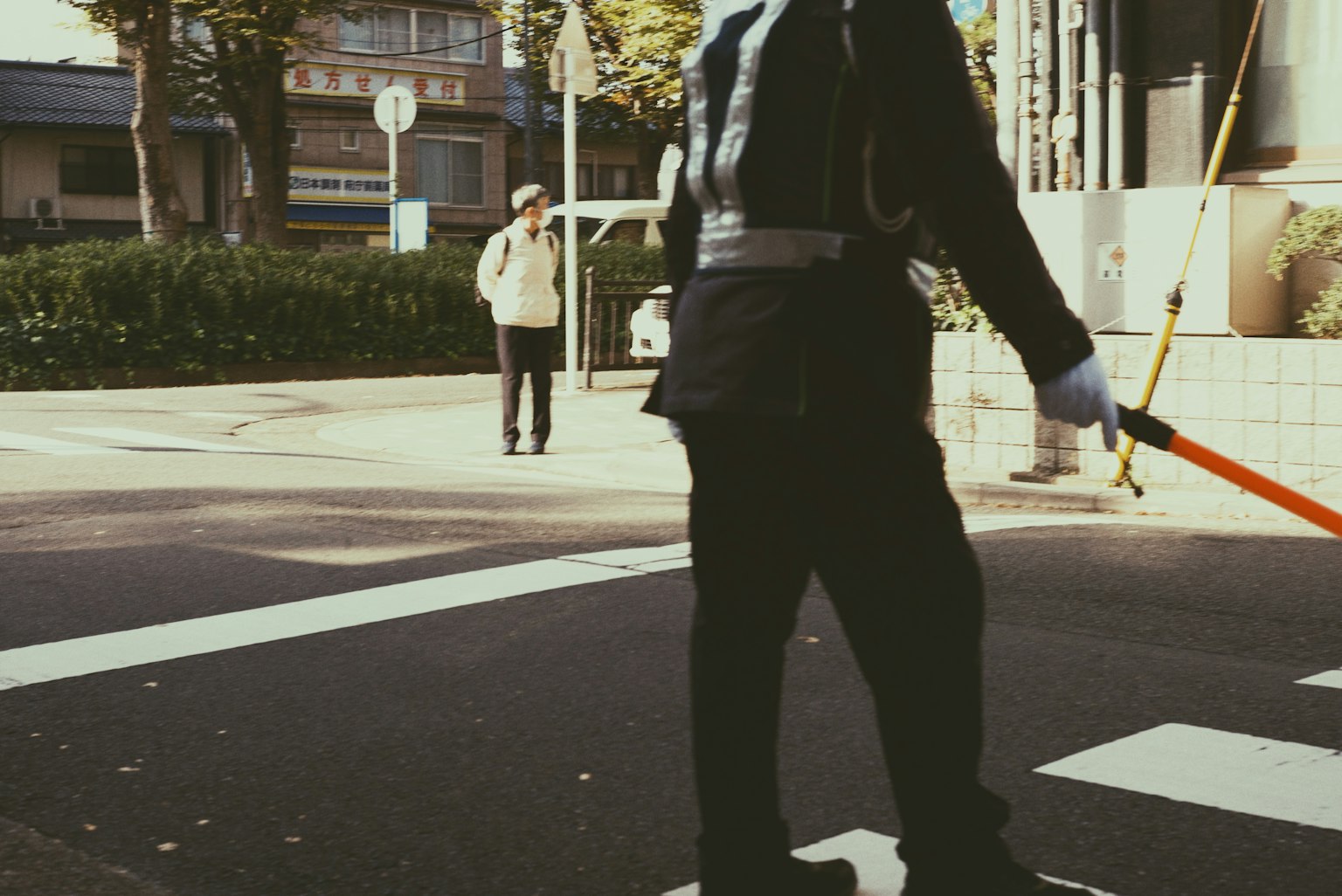 Police officer directing traffic at a crosswalk with a pedestrian in the background