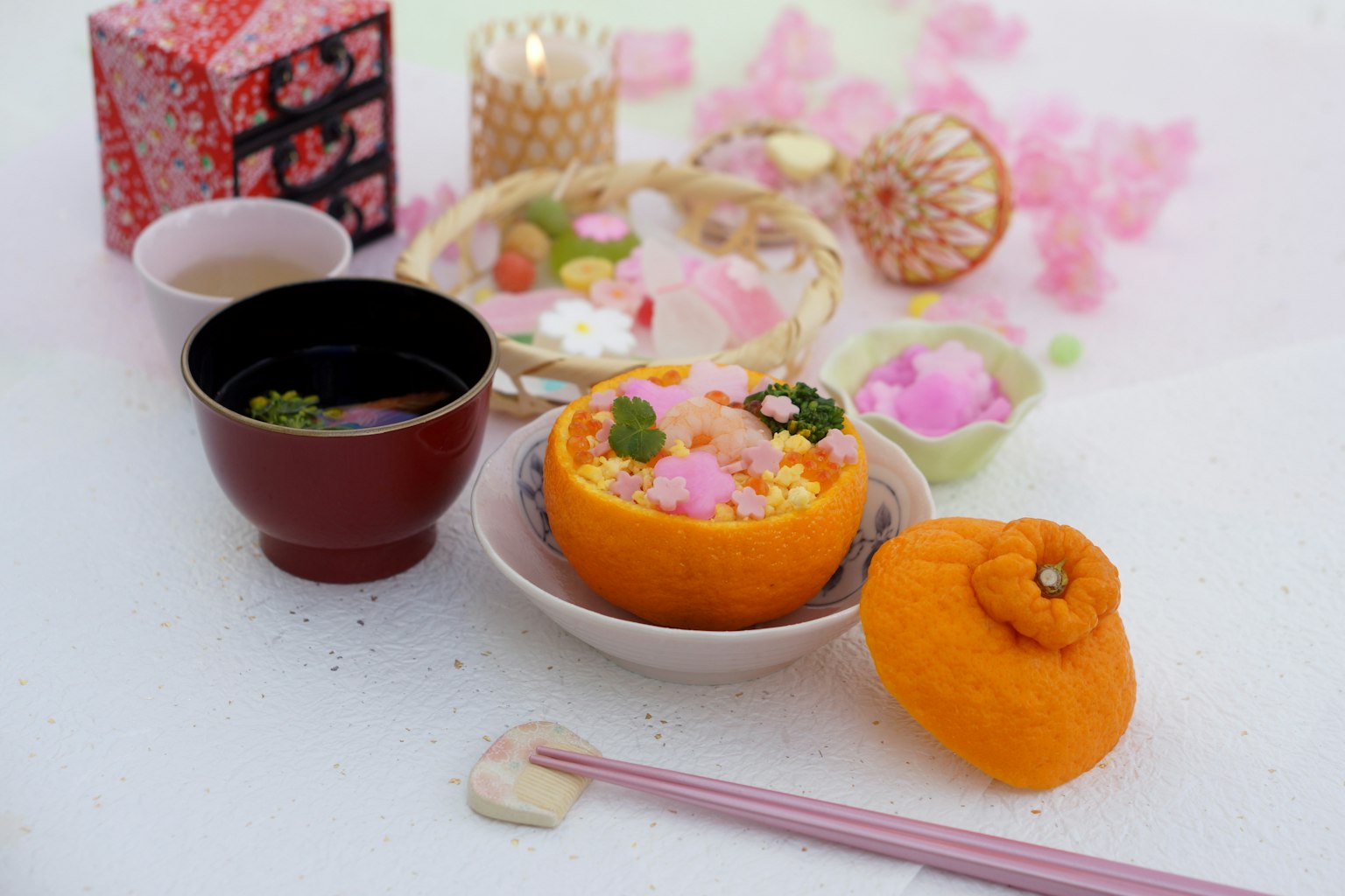 Colorful Japanese sweets presented on an orange plate with tea surrounded by flower petals