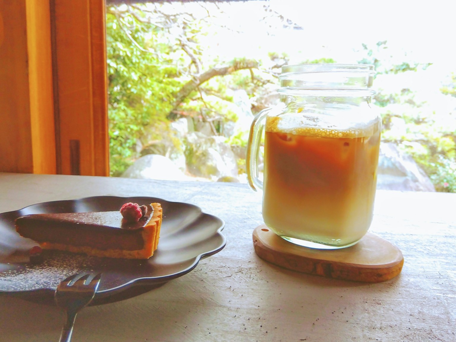 Café glacé et gâteau au chocolat sur une assiette avec une vue naturelle à l'extérieur de la fenêtre