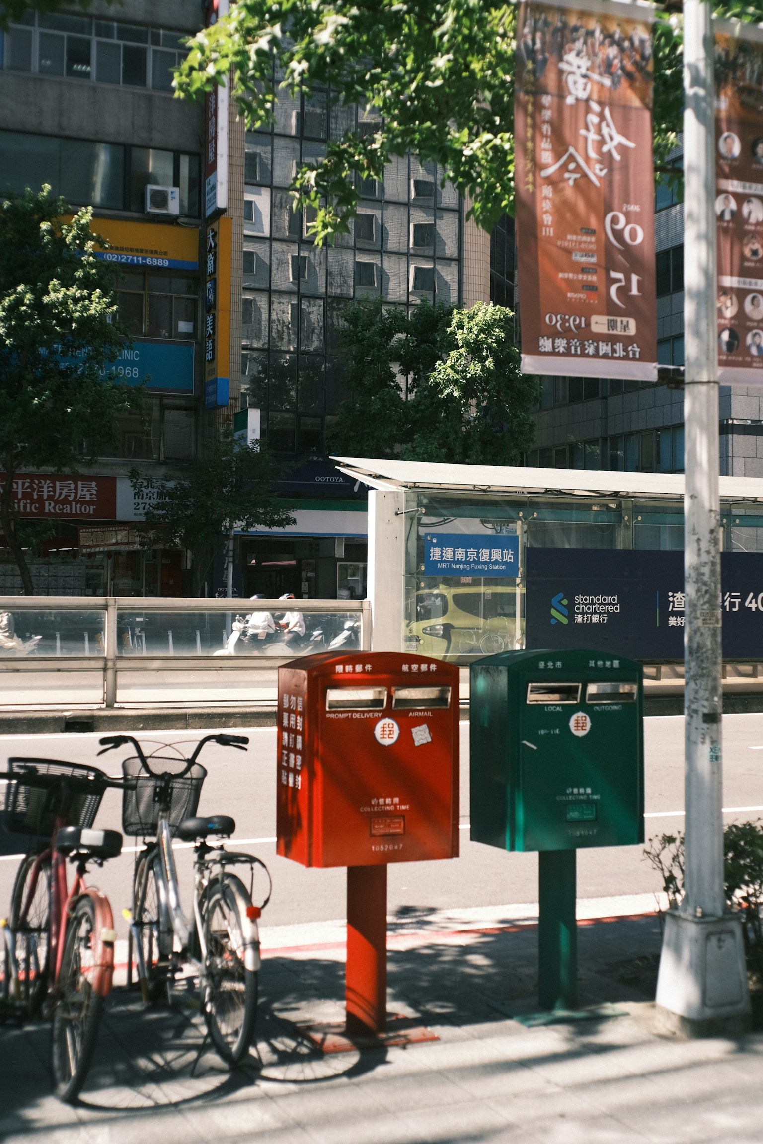 Straßenszene mit roten und grünen Briefkästen und Fahrrädern in der Nähe