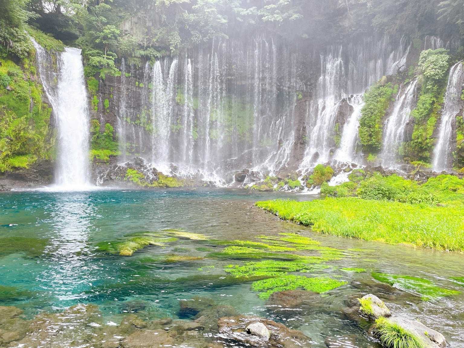 Air terjun yang indah dikelilingi oleh vegetasi subur dan air jernih