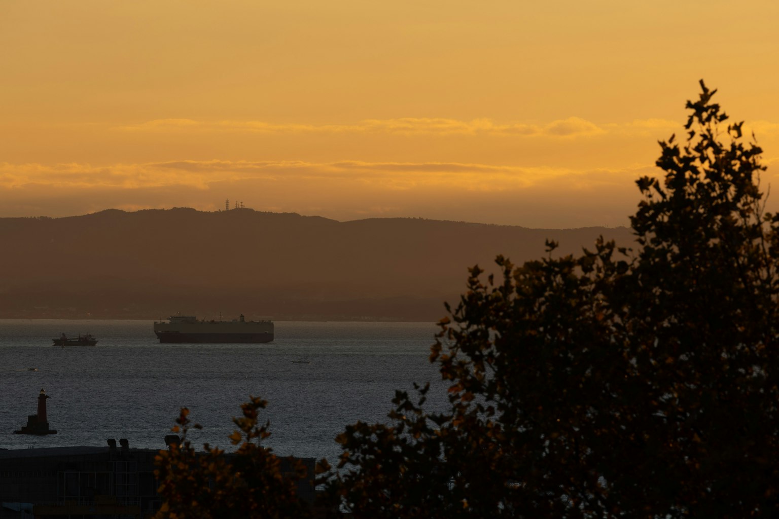 Silueta de montañas y barcos en el mar durante el atardecer