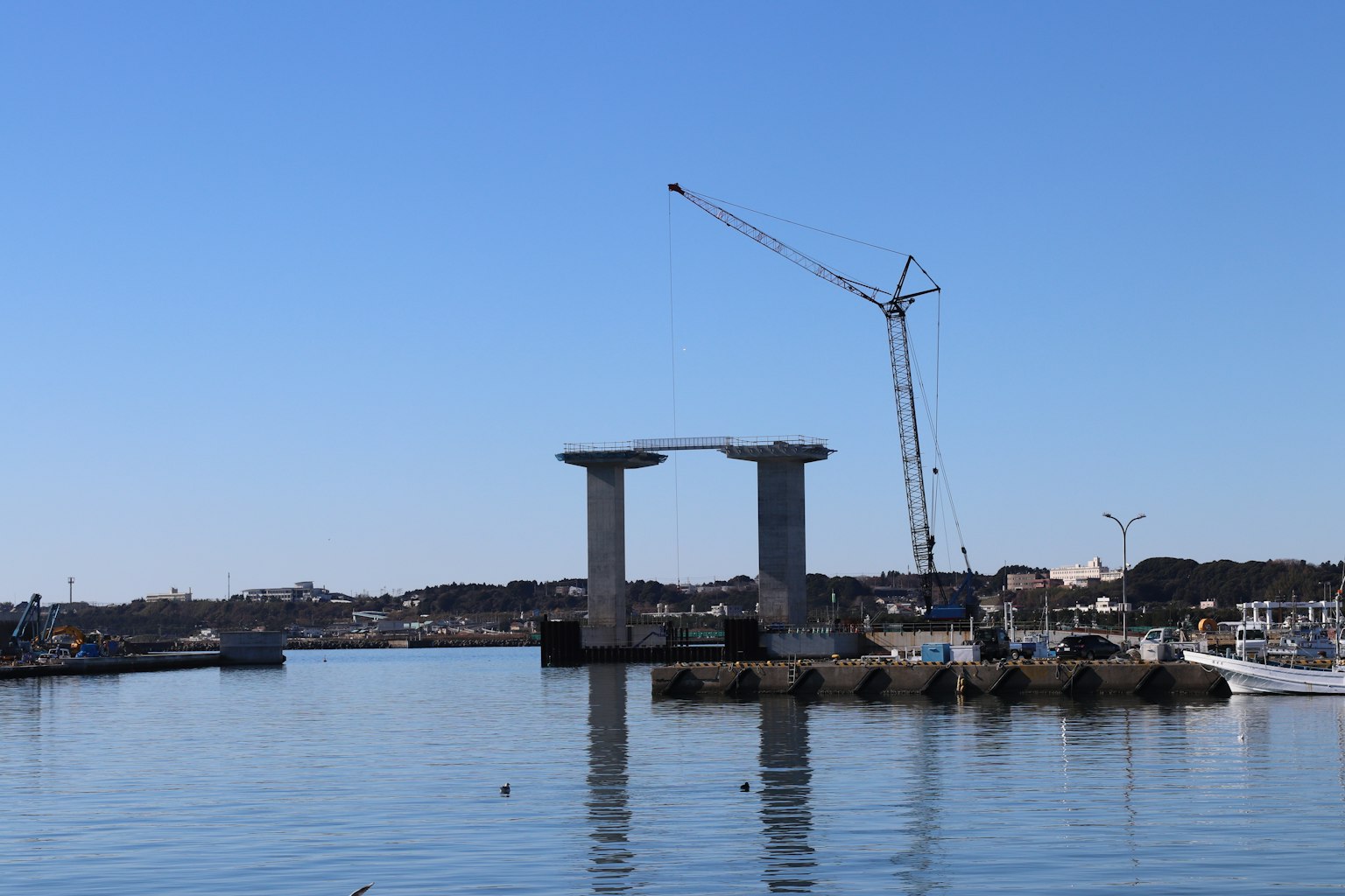 Construction site of a bridge with pillars and a crane over the water