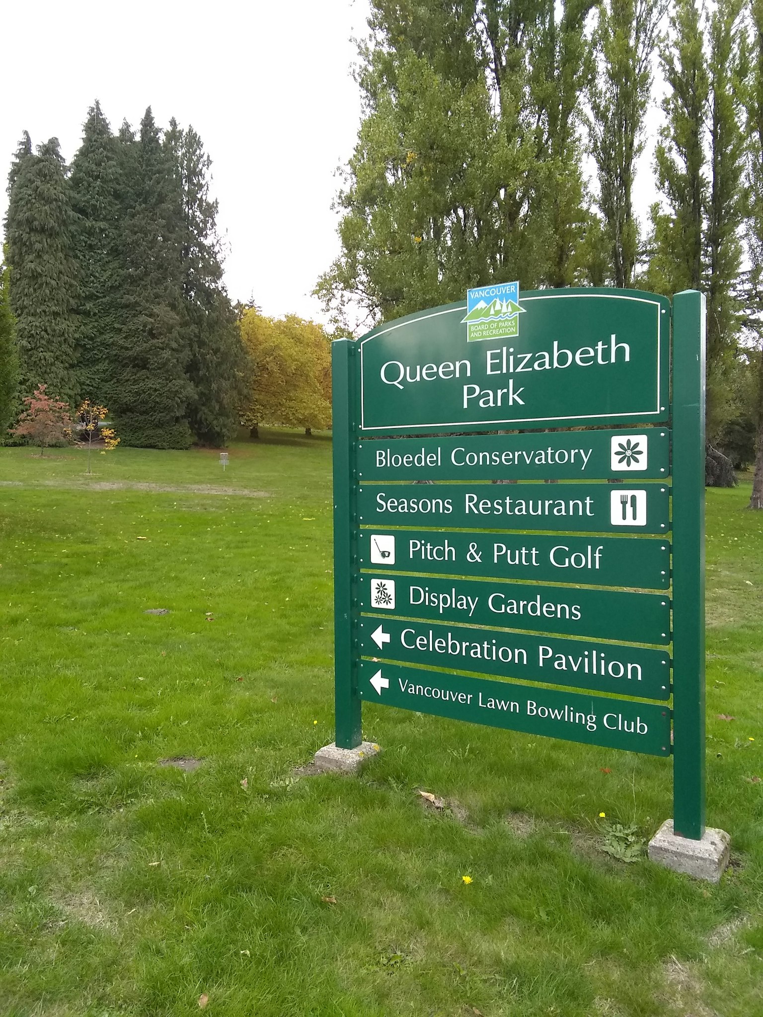 Papan informasi Taman Queen Elizabeth dengan latar belakang hijau dan teks putih yang mencantumkan atraksi dan fasilitas