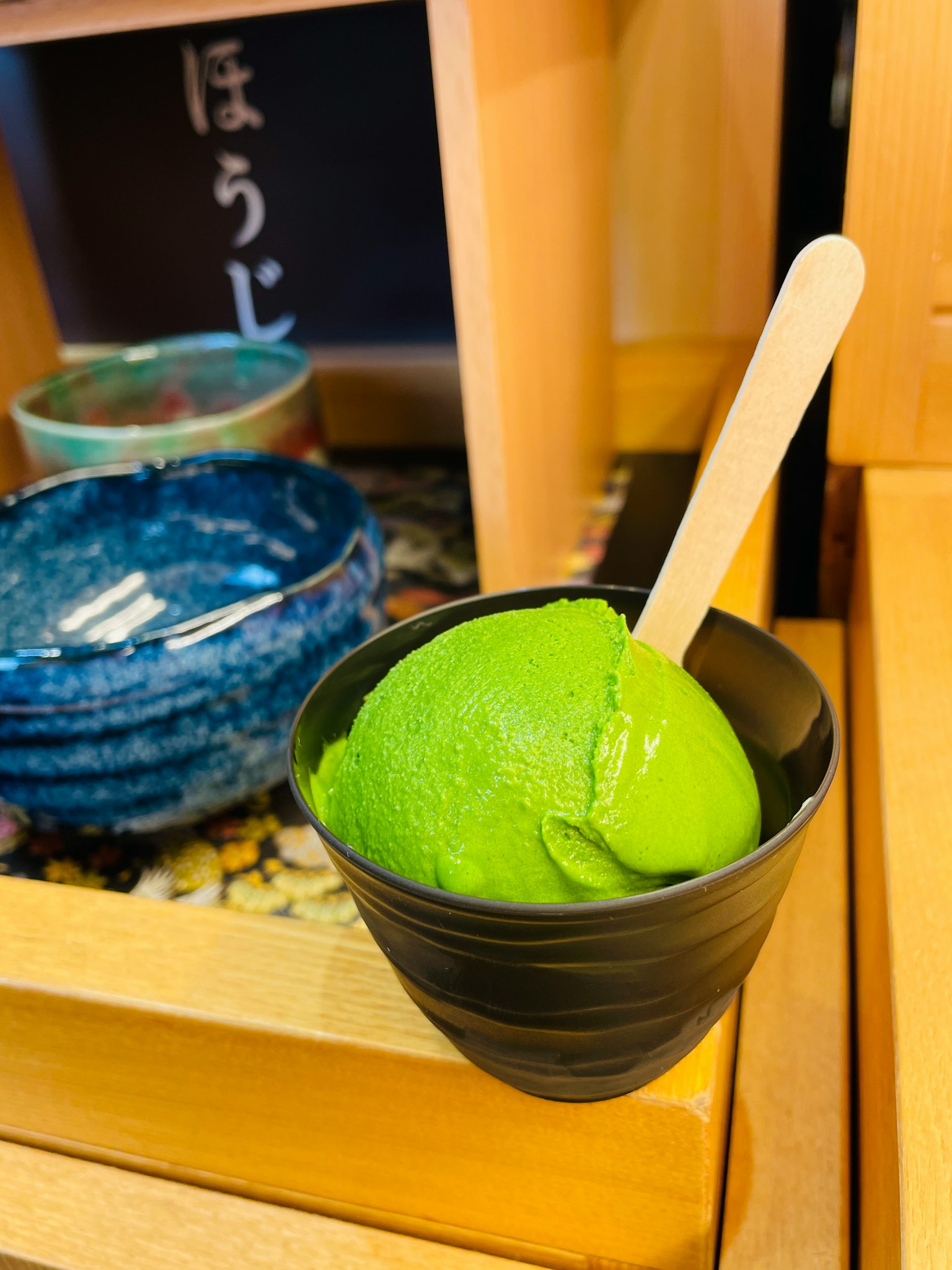 ไอศกรีมสีเขียวในถ้วยสีดำพร้อมช้อนไม้
