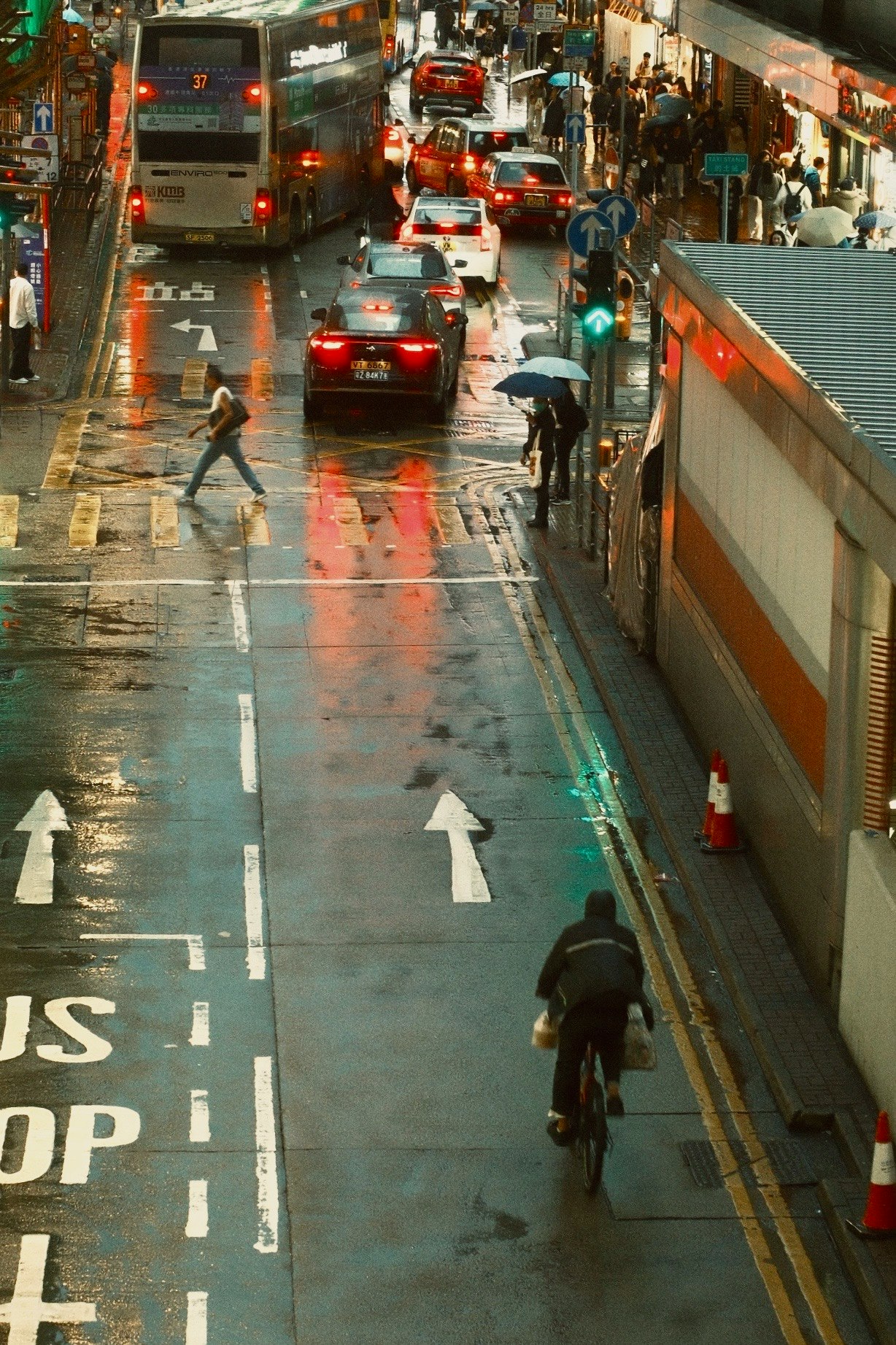 雨の路地を走る車と自転車のある街並み