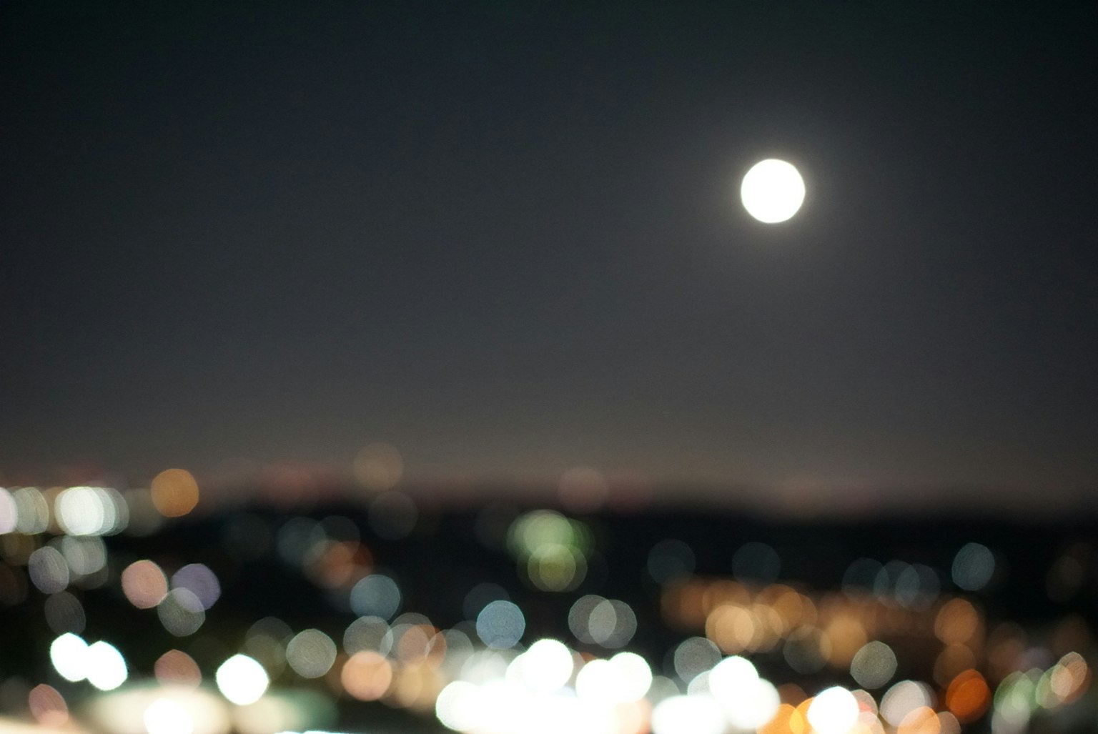 夜空中的满月和模糊的城市灯光
