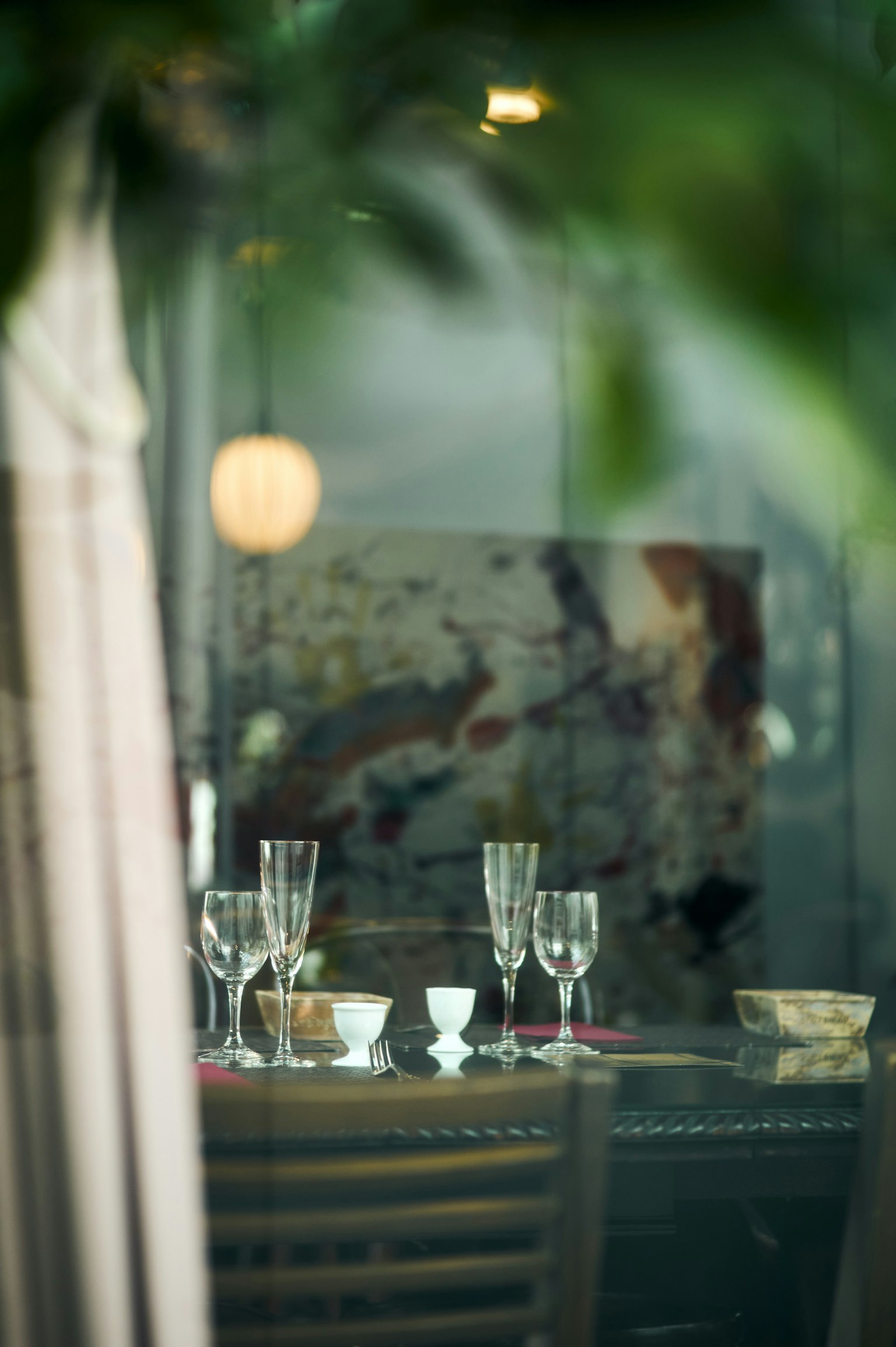 Mesa decorada con copas y platos con una obra de arte al fondo