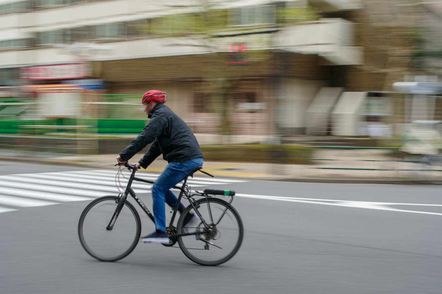 一位戴著紅色安全帽的男子在街上騎自行車
