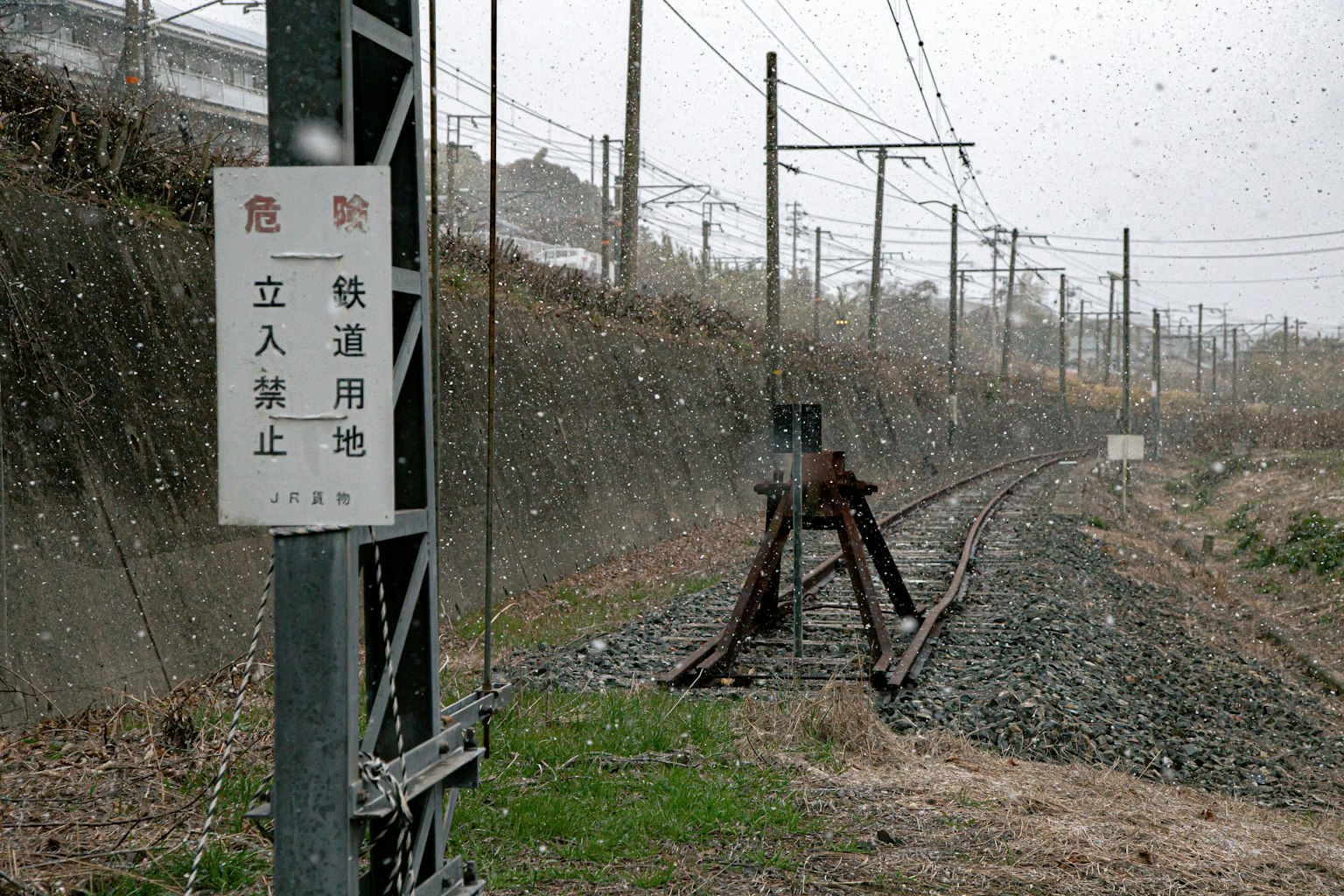 Escena ferroviaria nevada con un cartel y rieles