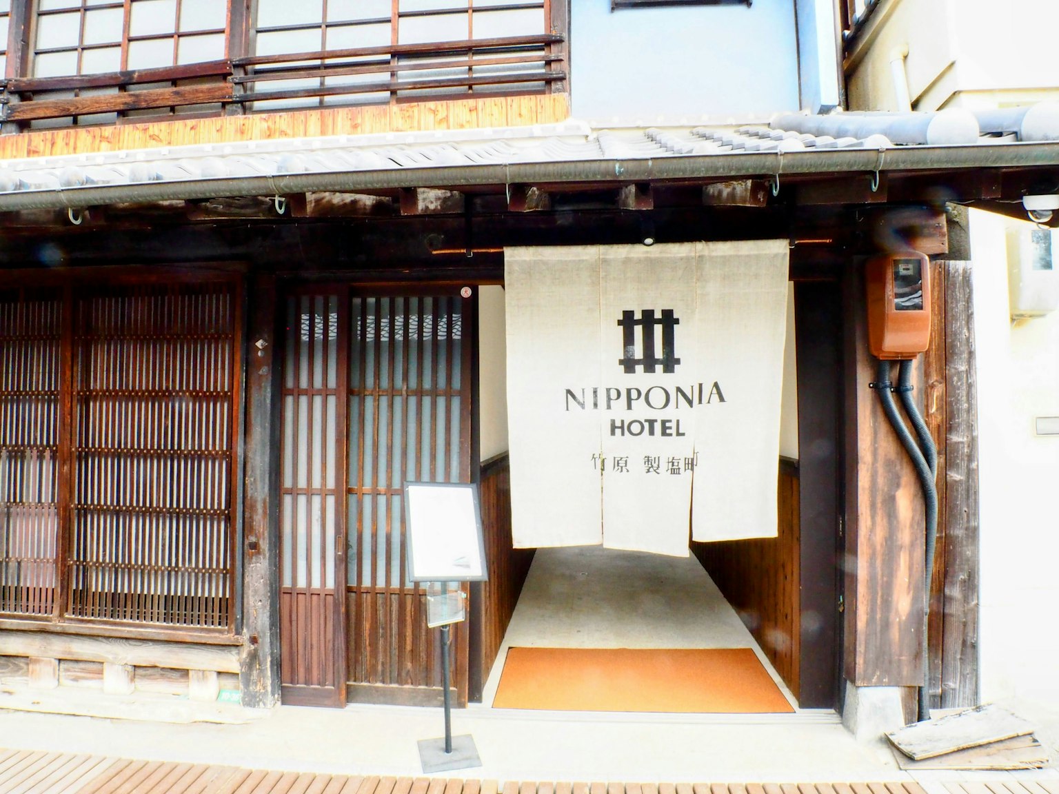 Entrance of a traditional Japanese hotel with a sign reading Nipponia Hotel