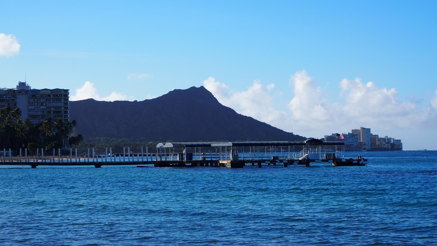 Landschaftsansicht des blauen Ozeans mit dem Diamond Head und einem Pier