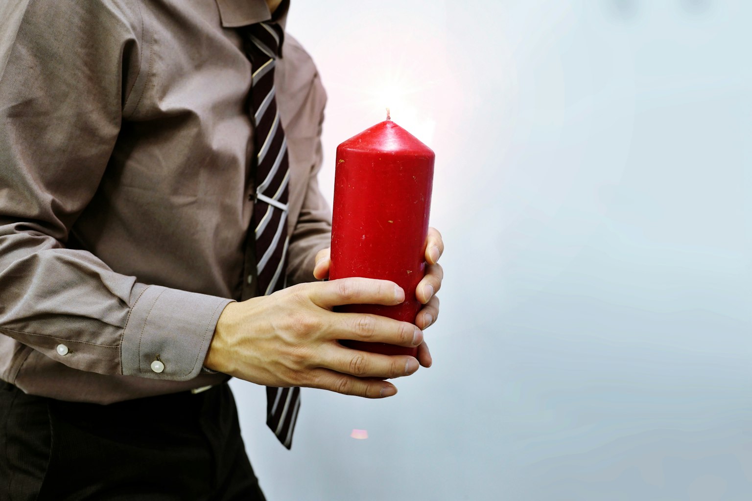 Un hombre sosteniendo una vela roja con una corbata