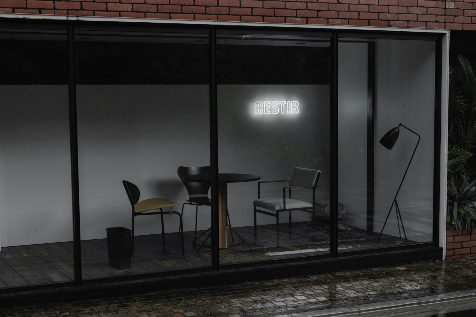 Ein einfacher Innenraum mit einem Tisch und Stühlen bei schwachem Licht