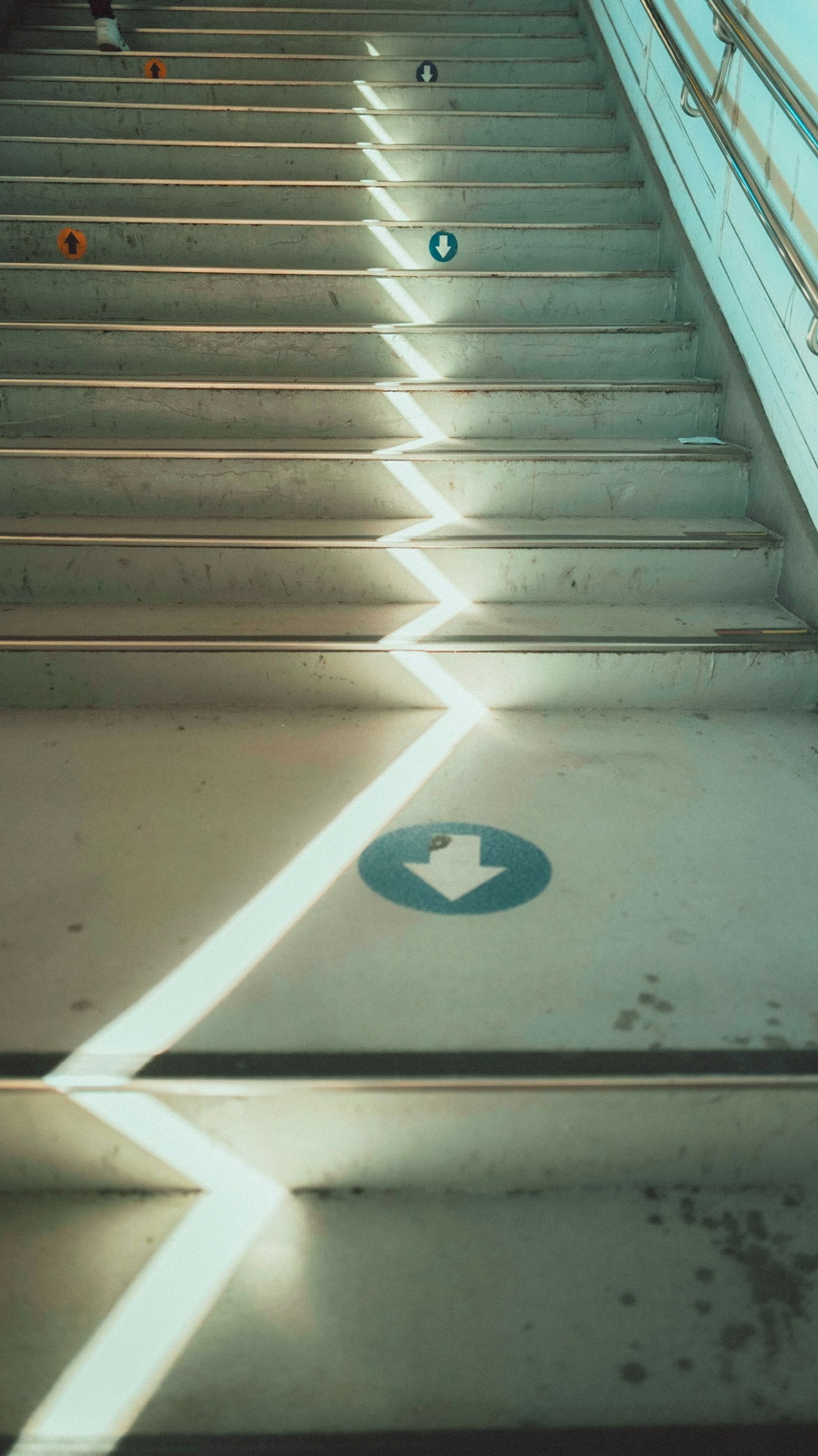 Escalier avec un motif de lumière en zigzag et un panneau fléché bleu