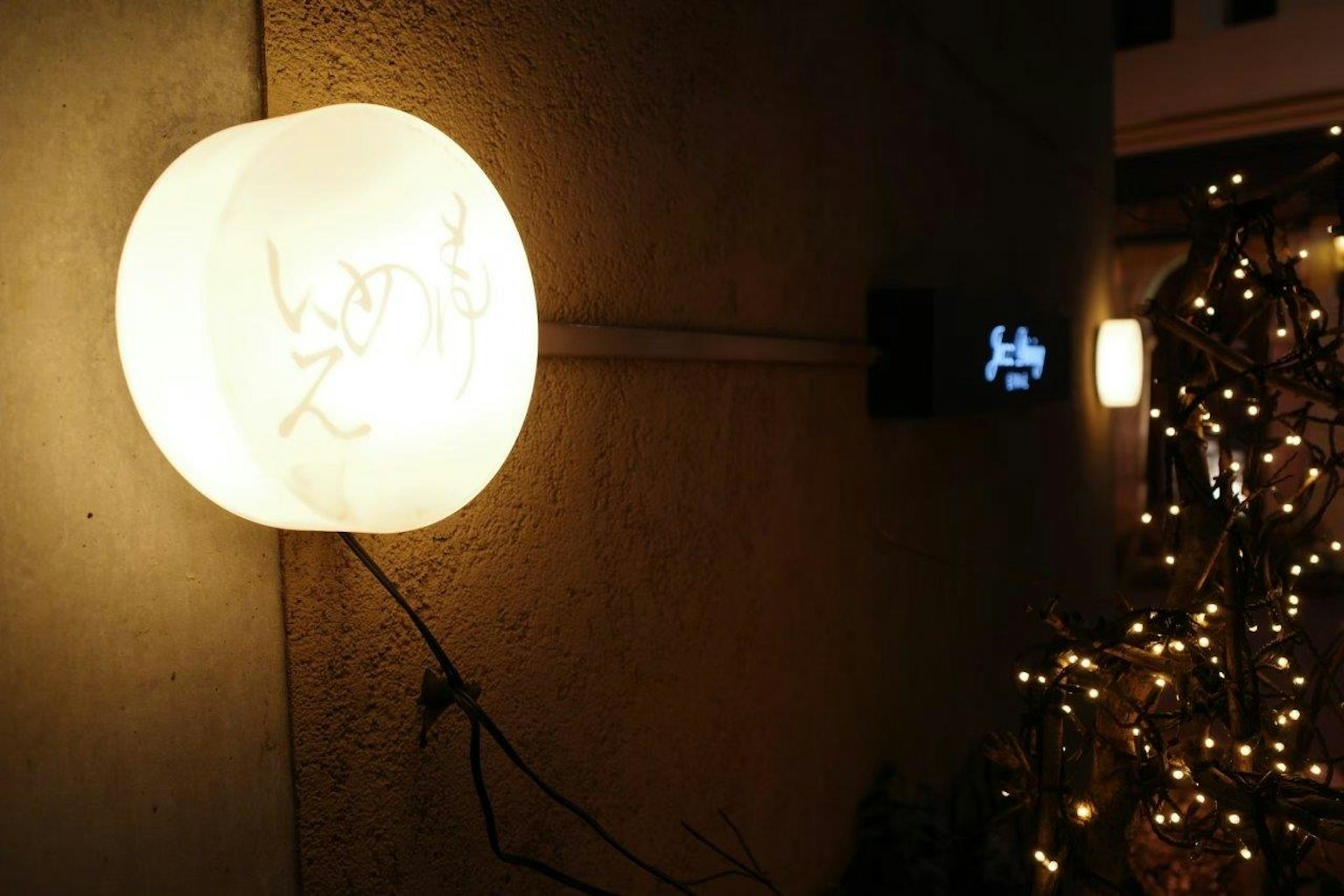 Sebuah lampu putih besar dipasang di dinding dengan lampu dekoratif di latar belakang