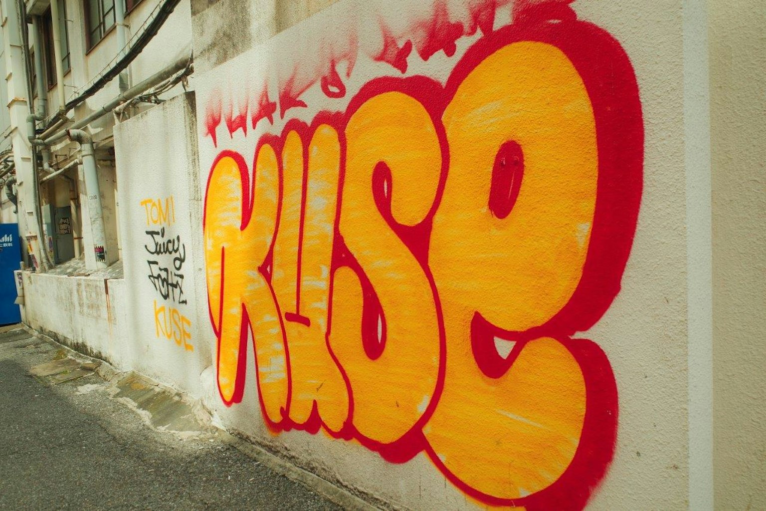 ศิลปะกราฟฟิติตามผนังที่มีคำว่า 'KUSE' เป็นสีแดงและสีส้ม
