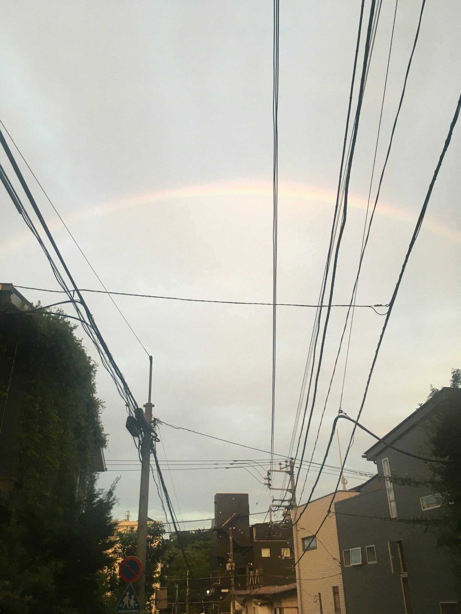 天空中淡淡的彩虹與城市景觀中的電線交錯