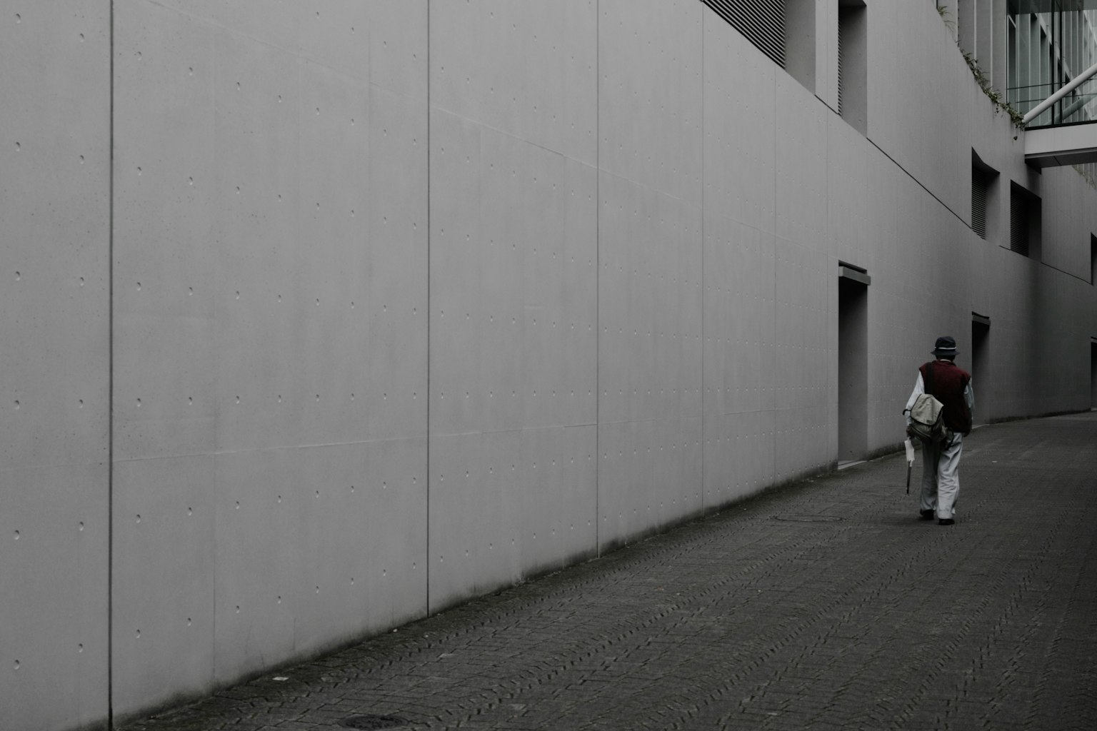 Una persona caminando junto a una pared gris