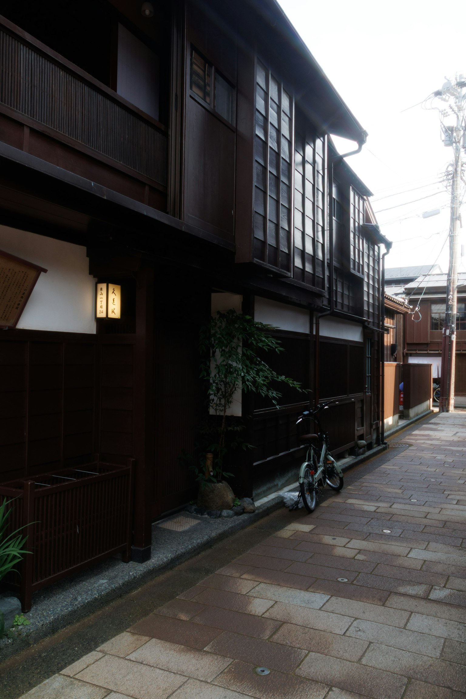 Schmale Gasse mit traditionellen Holzhäusern und einem Fahrrad in einer japanischen Stadt
