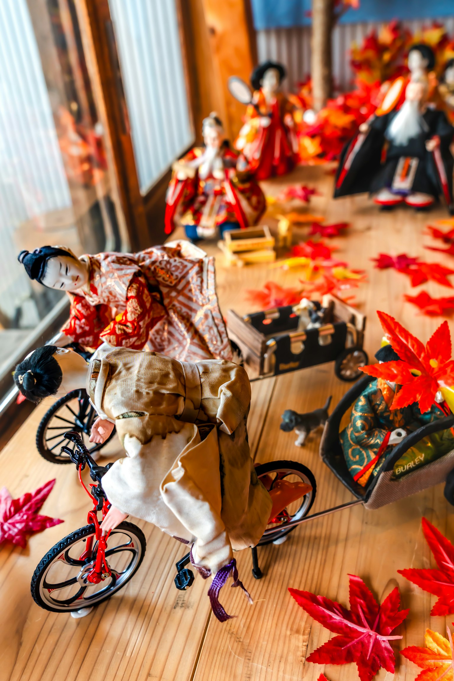 Muñecas japonesas tradicionales exhibidas en una mesa con hojas de otoño