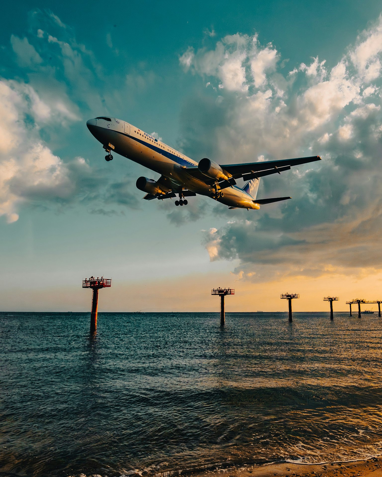 일몰에 흩어져 있는 구름 위로 평화로운 바다를 나는 비행기