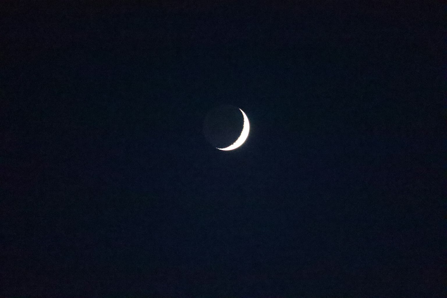 Bulan sabit tipis mengapung di langit gelap