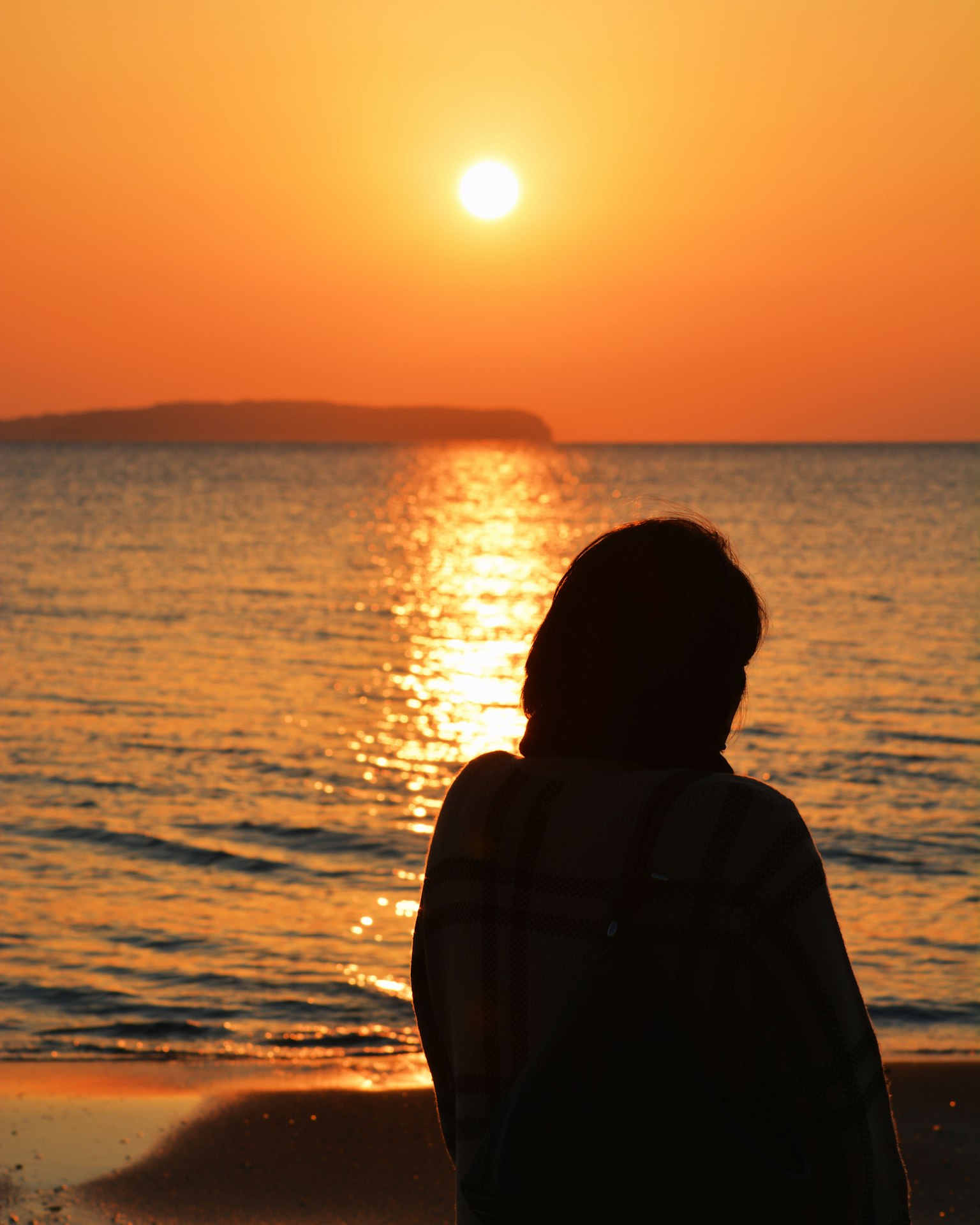 Silhouette of a person standing on the beach against the sunset