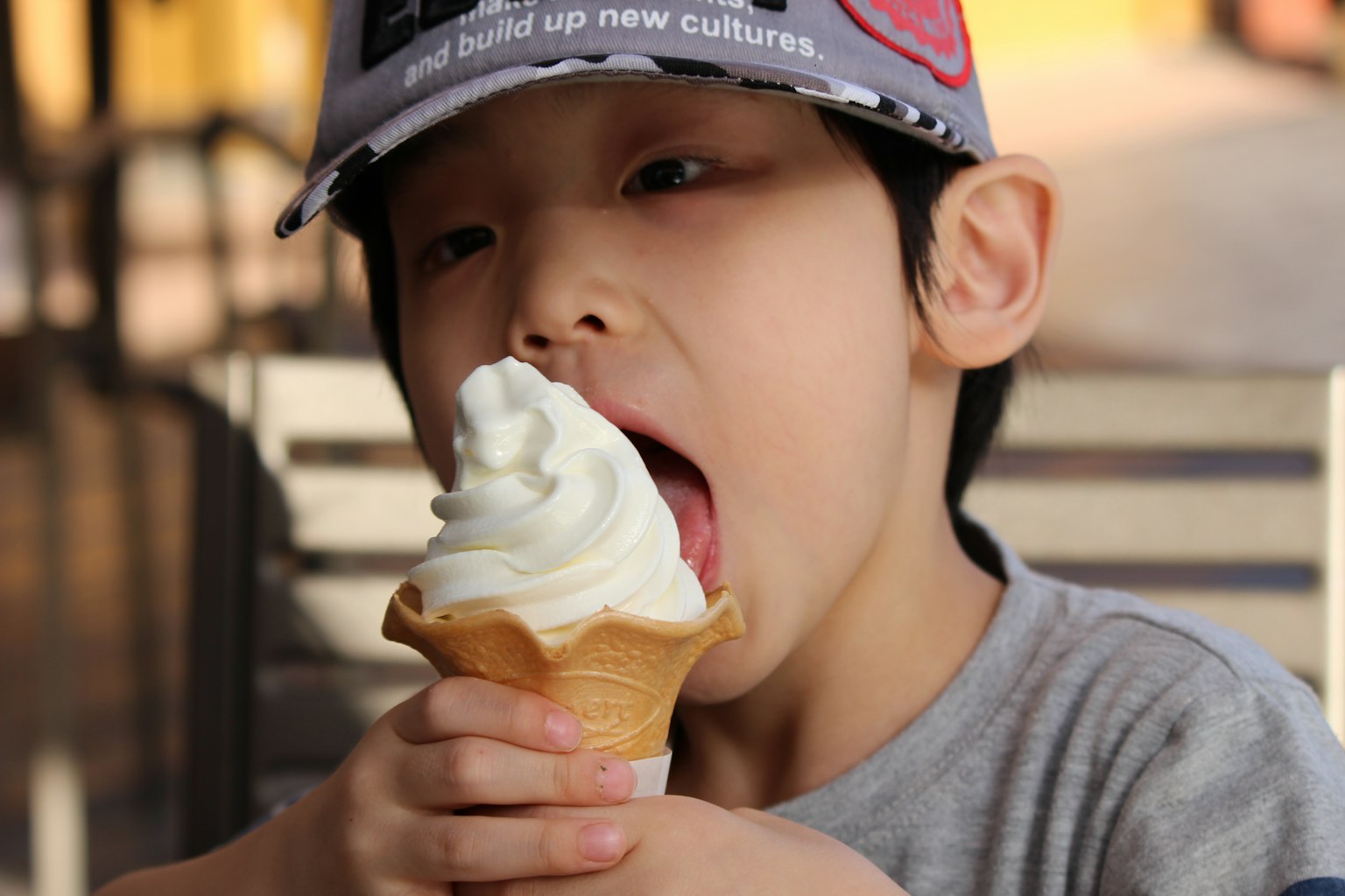 Seorang anak yang makan es krim seorang anak laki-laki yang mengenakan topi sedang menjilati es krim lembut