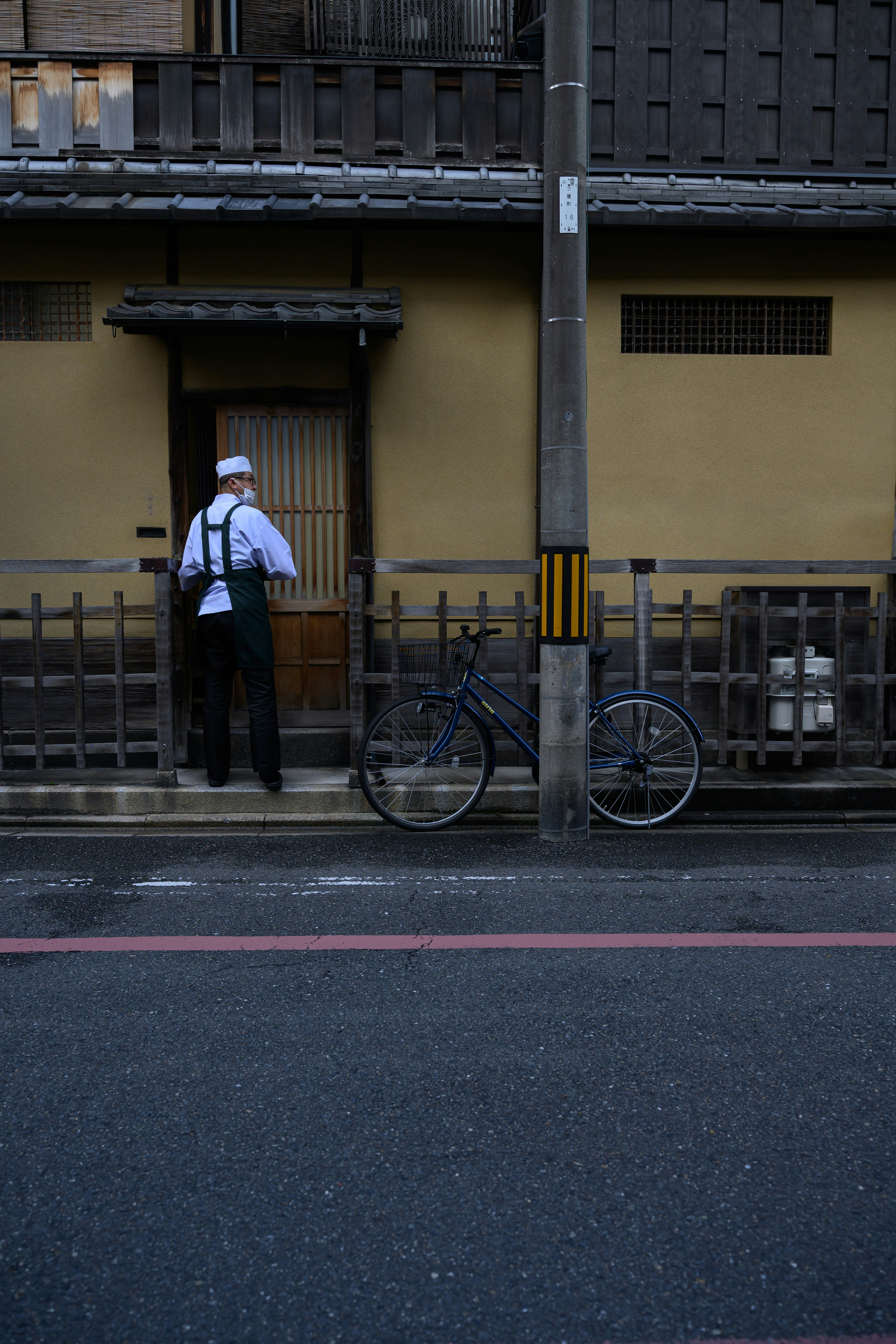 京都の路地で自転車と立つ白い帽子の人物