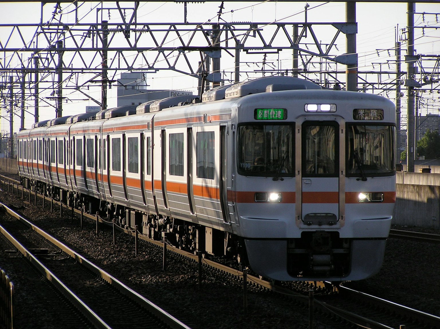 Un treno giapponese che corre su binari con fili aerei