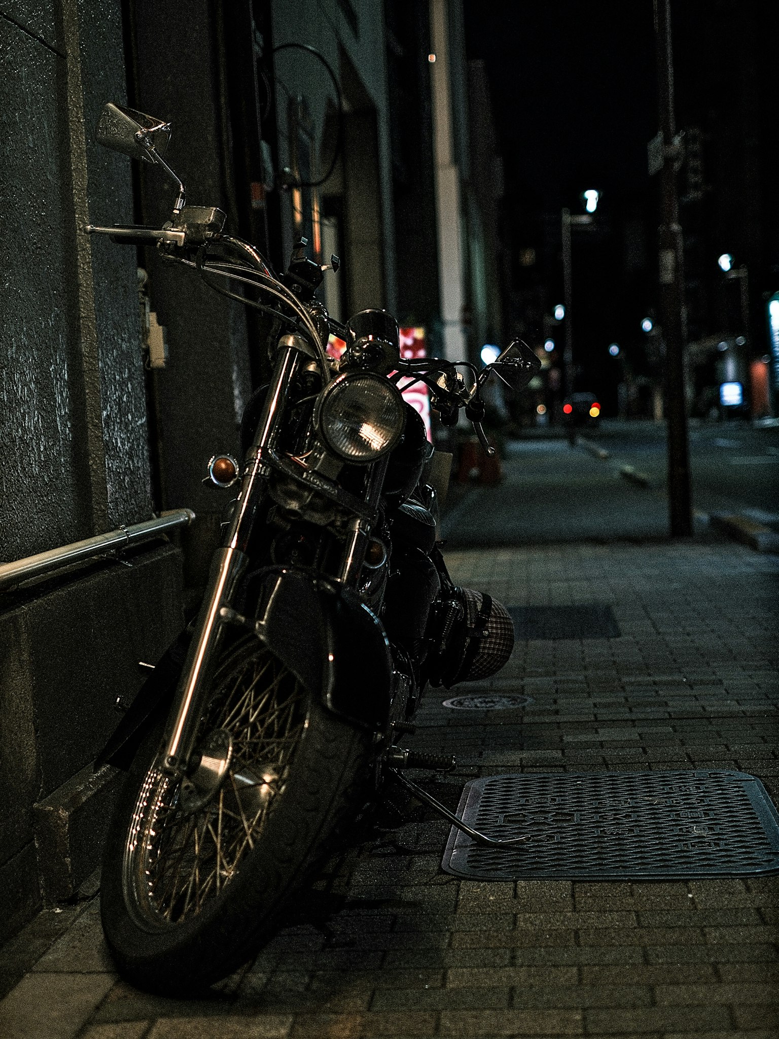 夜の街角に停まる黒いバイクのクローズアップ