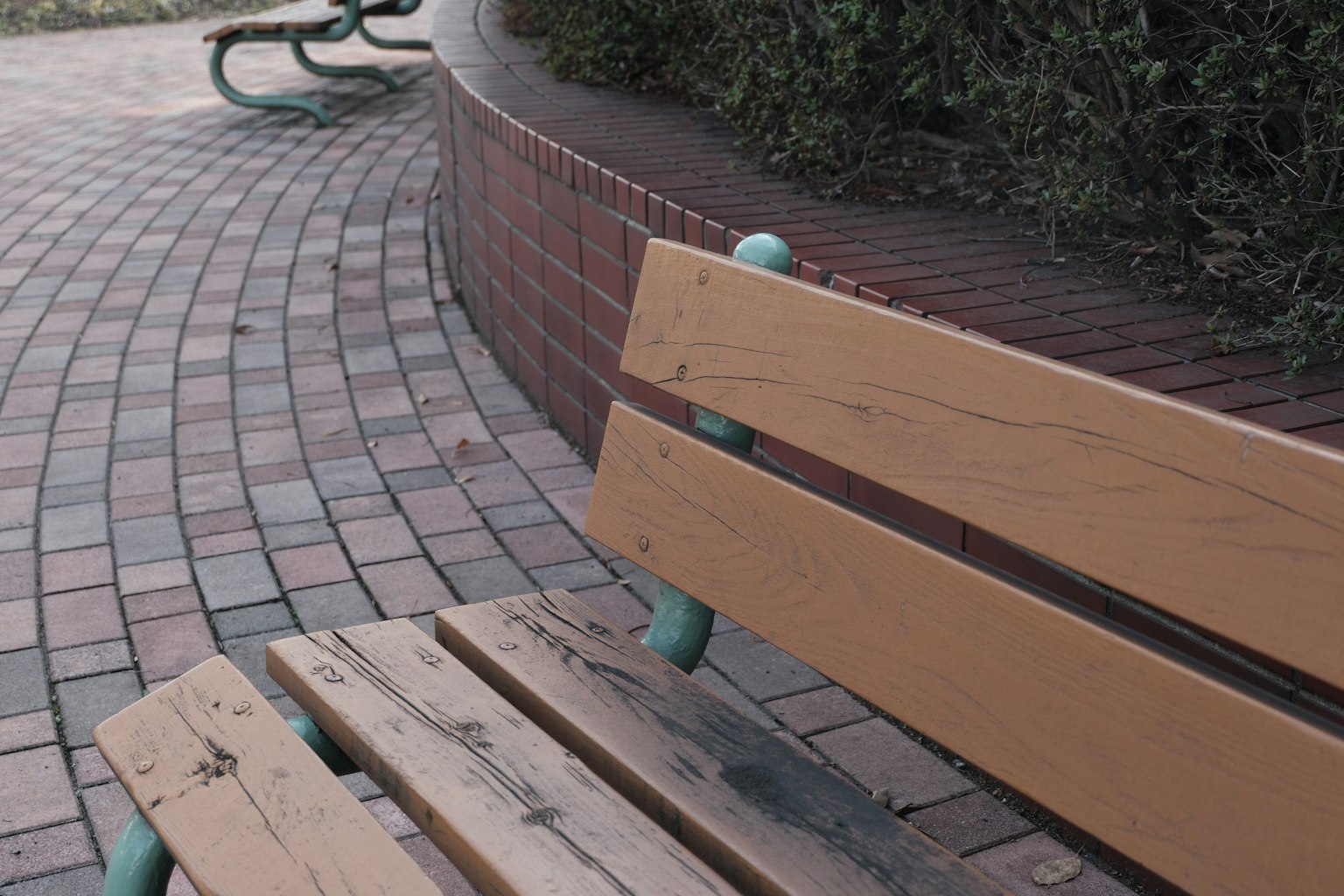 Close-up of a park bench and brick pathway