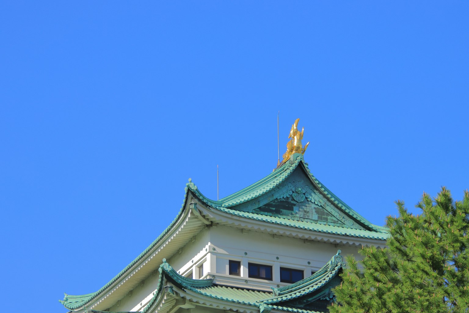 Partie d'un château japonais traditionnel avec un toit vert sous un ciel bleu