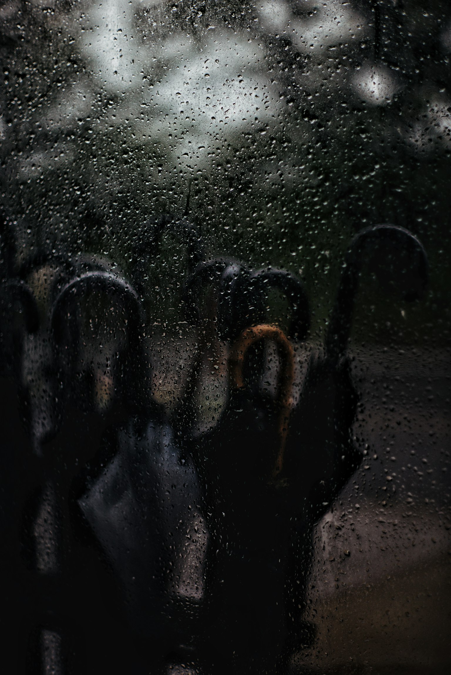 Une vue d'ombrelles alignées derrière une fenêtre mouillée par la pluie