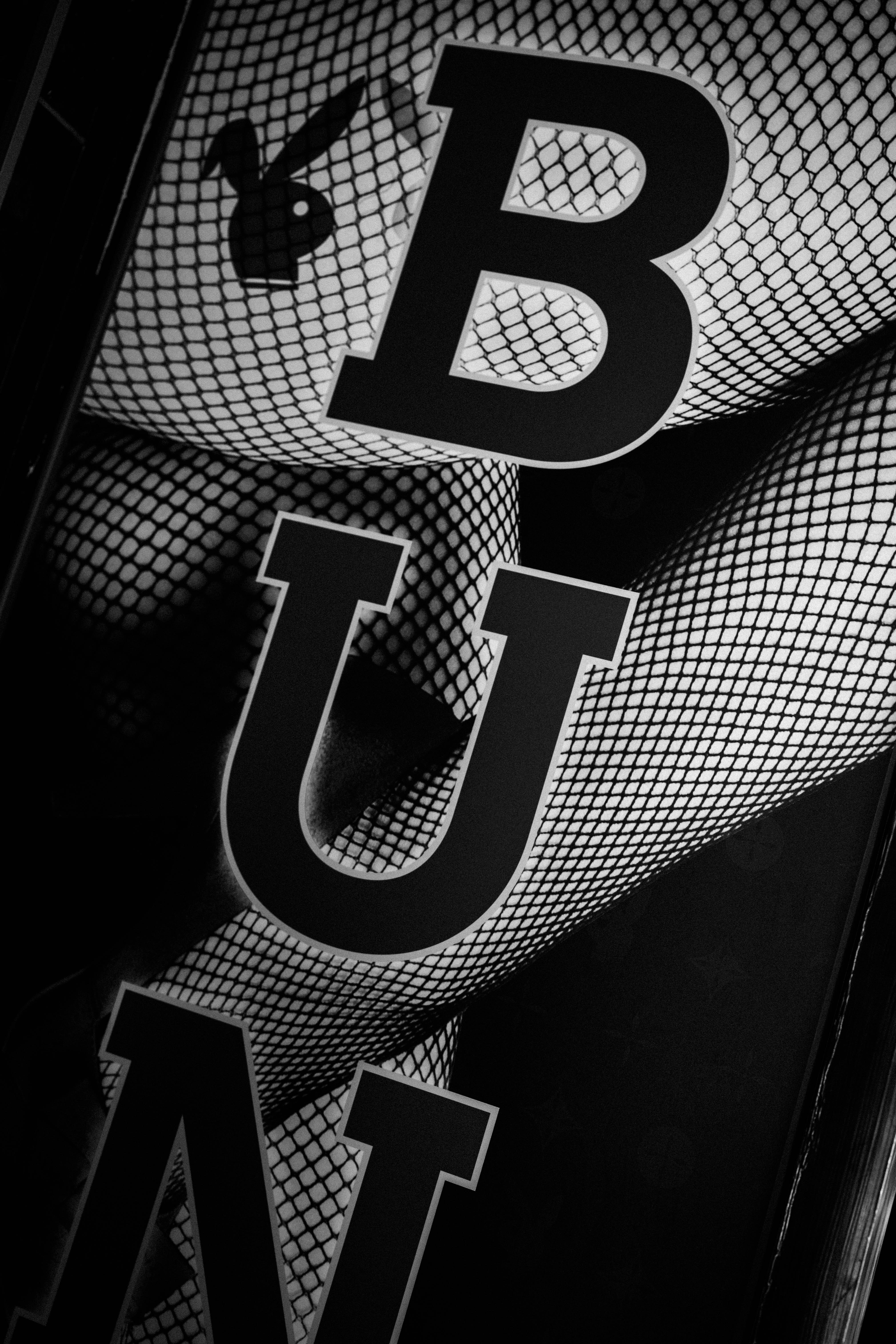 メッシュ状の背景に浮かぶ大きな「B」ロゴと「U」文字