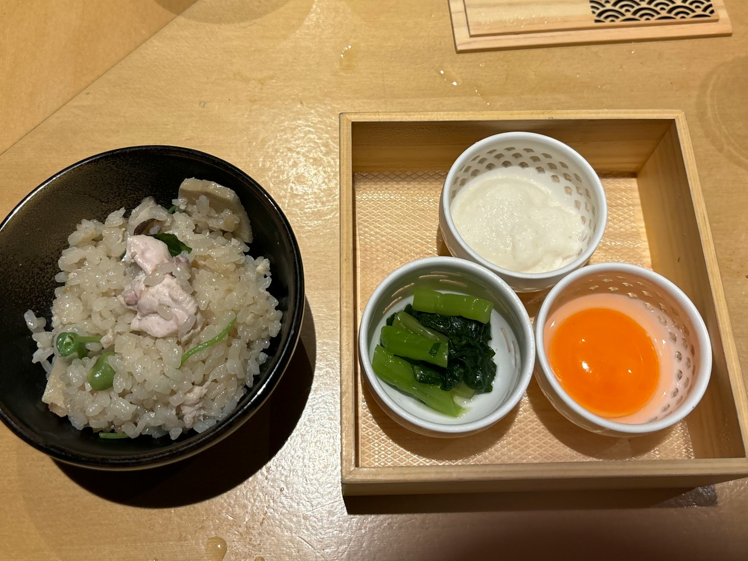 米饭配鸡肉和蔬菜的碗 旁边有绿色蔬菜和蛋黄