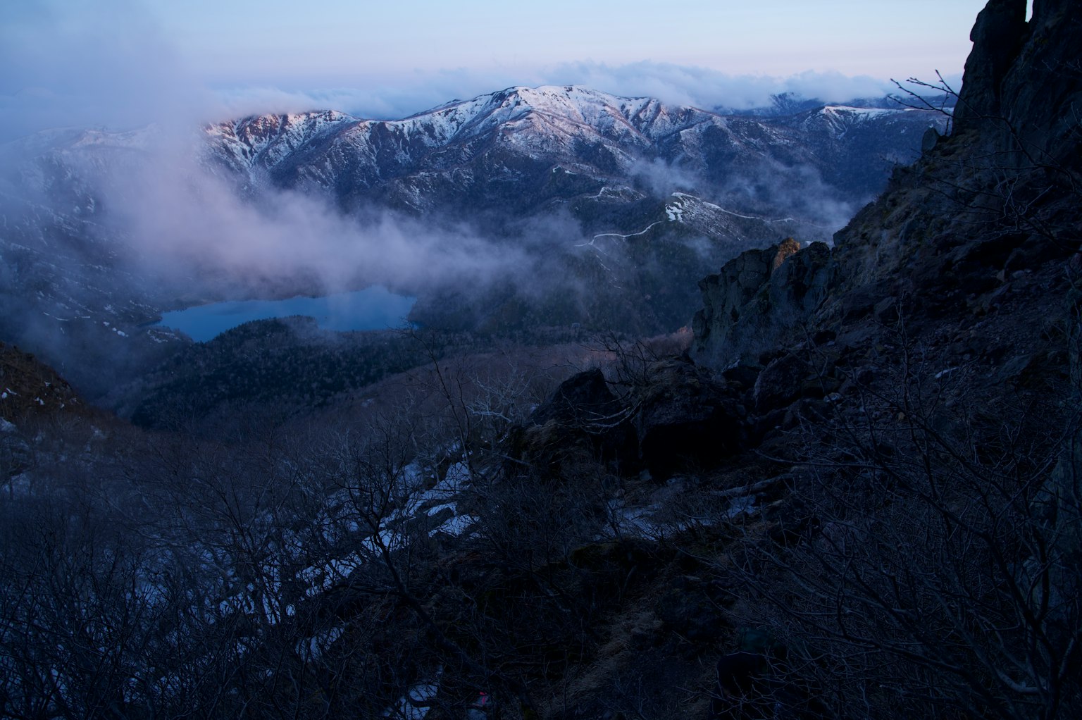 Mountain landscape shrouded in mist with a blue lake