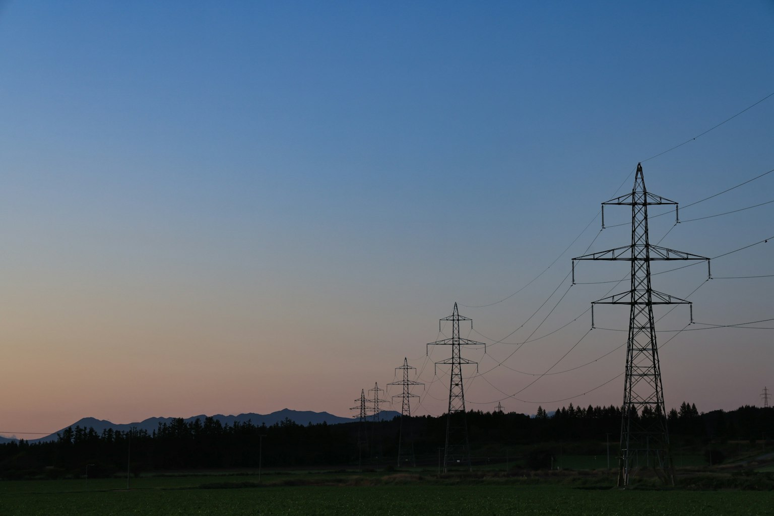 夕暮れ時の電柱と山々のシルエット