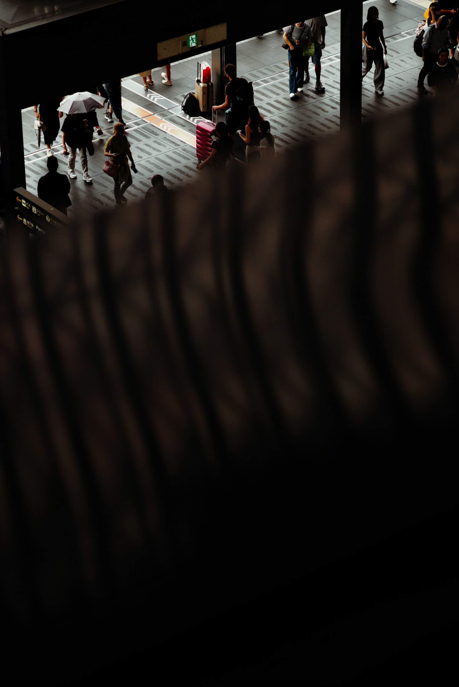 Vista di una stazione ferroviaria affollata con persone che camminano e ombre