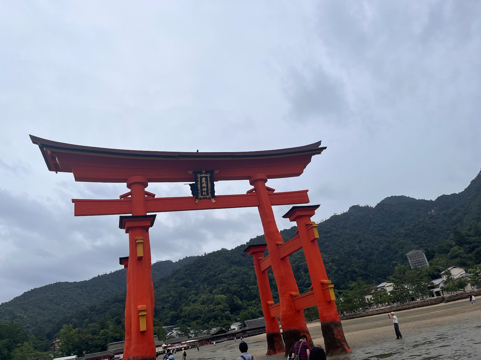 Torii rosso che si erge nel mare con montagne sullo sfondo
