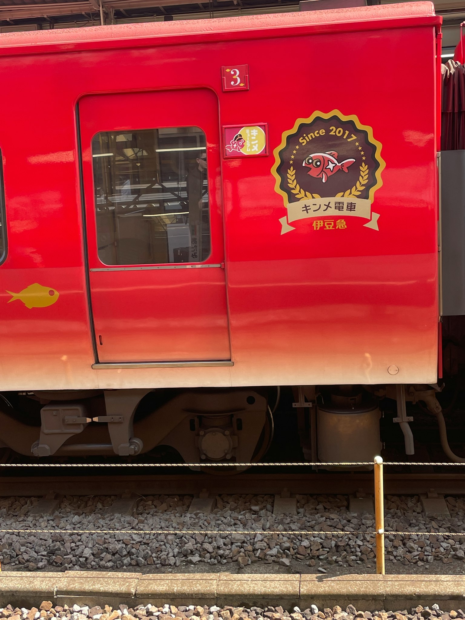 Side view of a red train featuring a logo and window