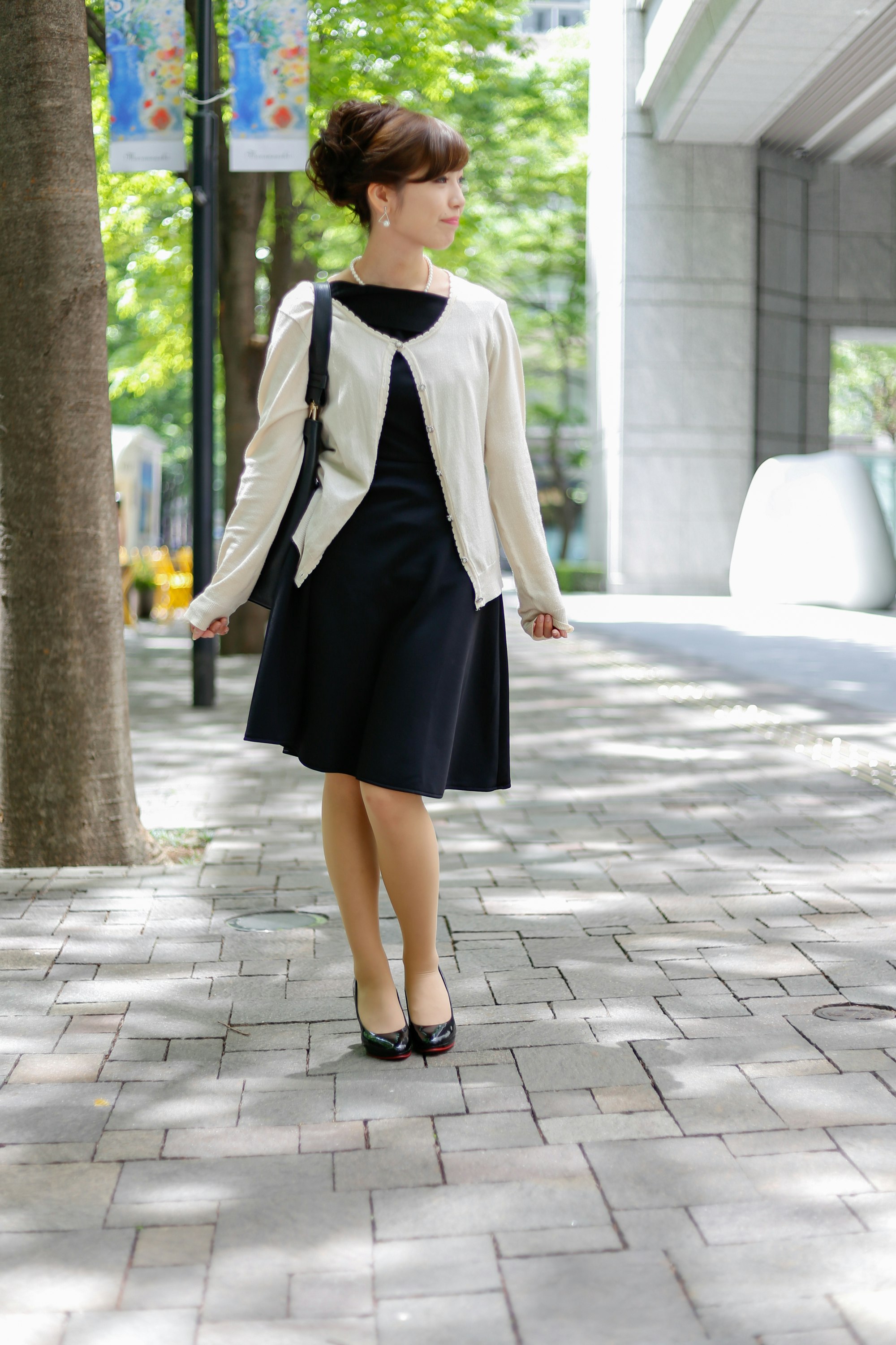 並木道を歩く黒いワンピースの女性