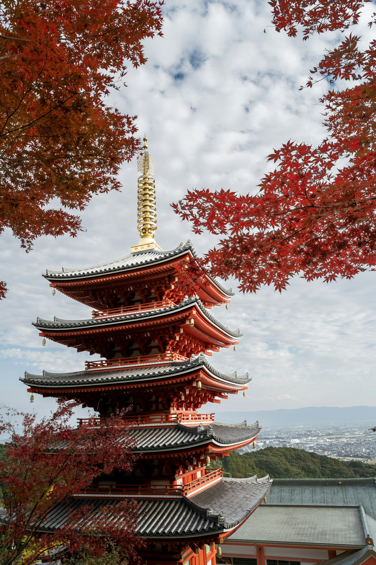 Fünfstöckige Pagode umgeben von roten Herbstblättern und blauem Himmel