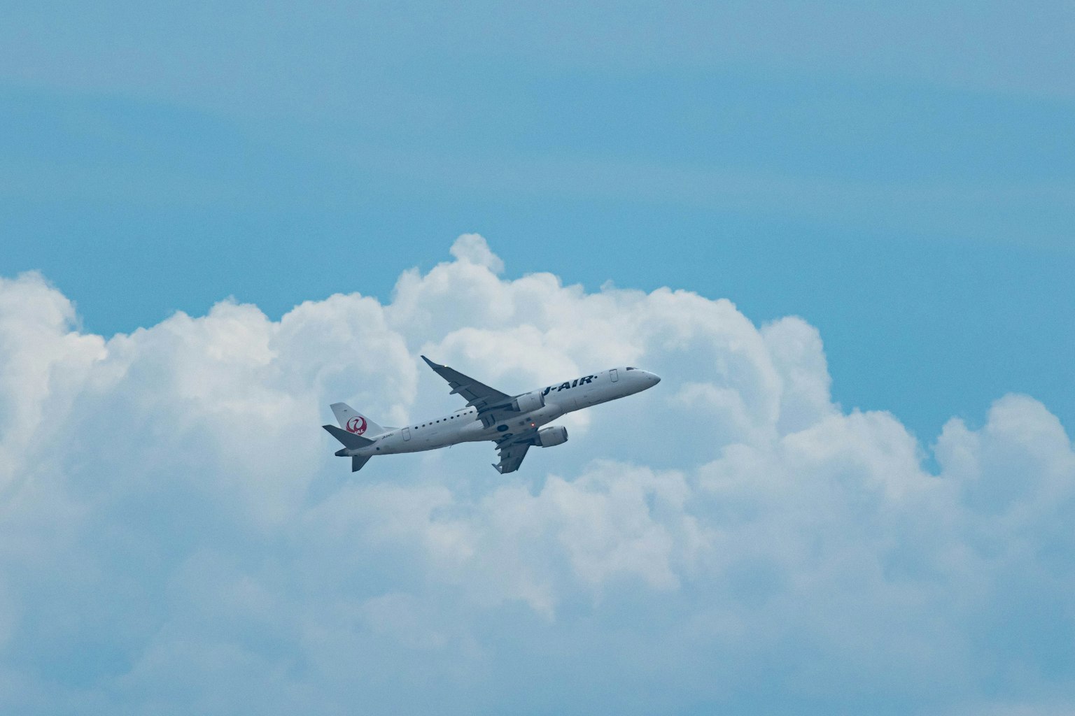 Avión volando en un cielo azul con nubes blancas