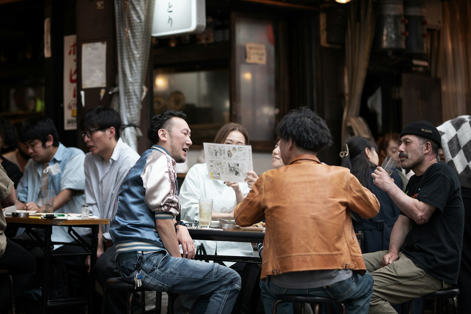 Group of people enjoying conversation at a lively izakaya