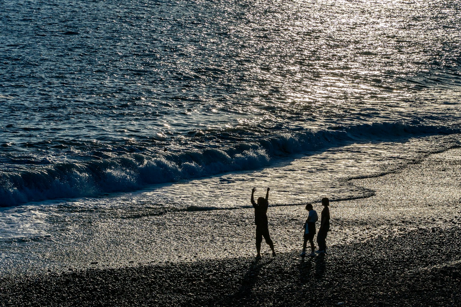 孩子们在海滩上玩耍的剪影与闪耀的海浪