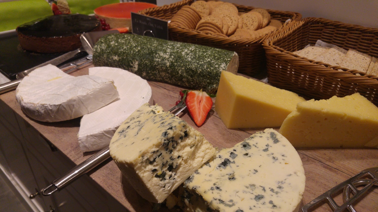 Un assortimento di formaggi, incluso il formaggio blu e cracker su un tagliere di legno