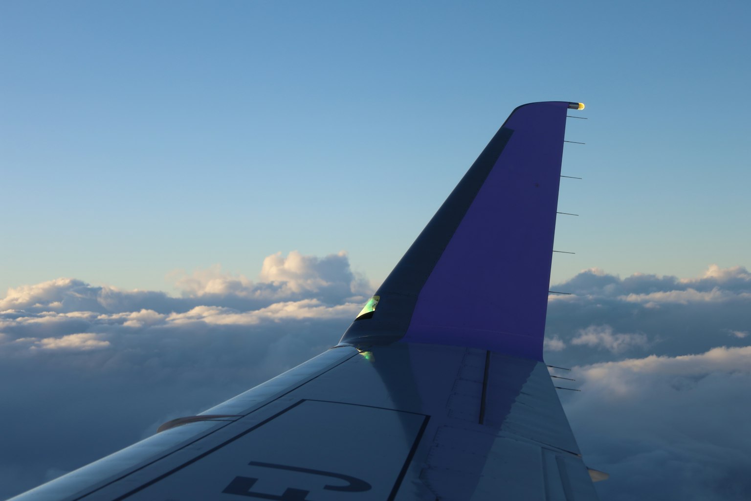 Ala di aereo contro uno sfondo di nuvole e cielo blu